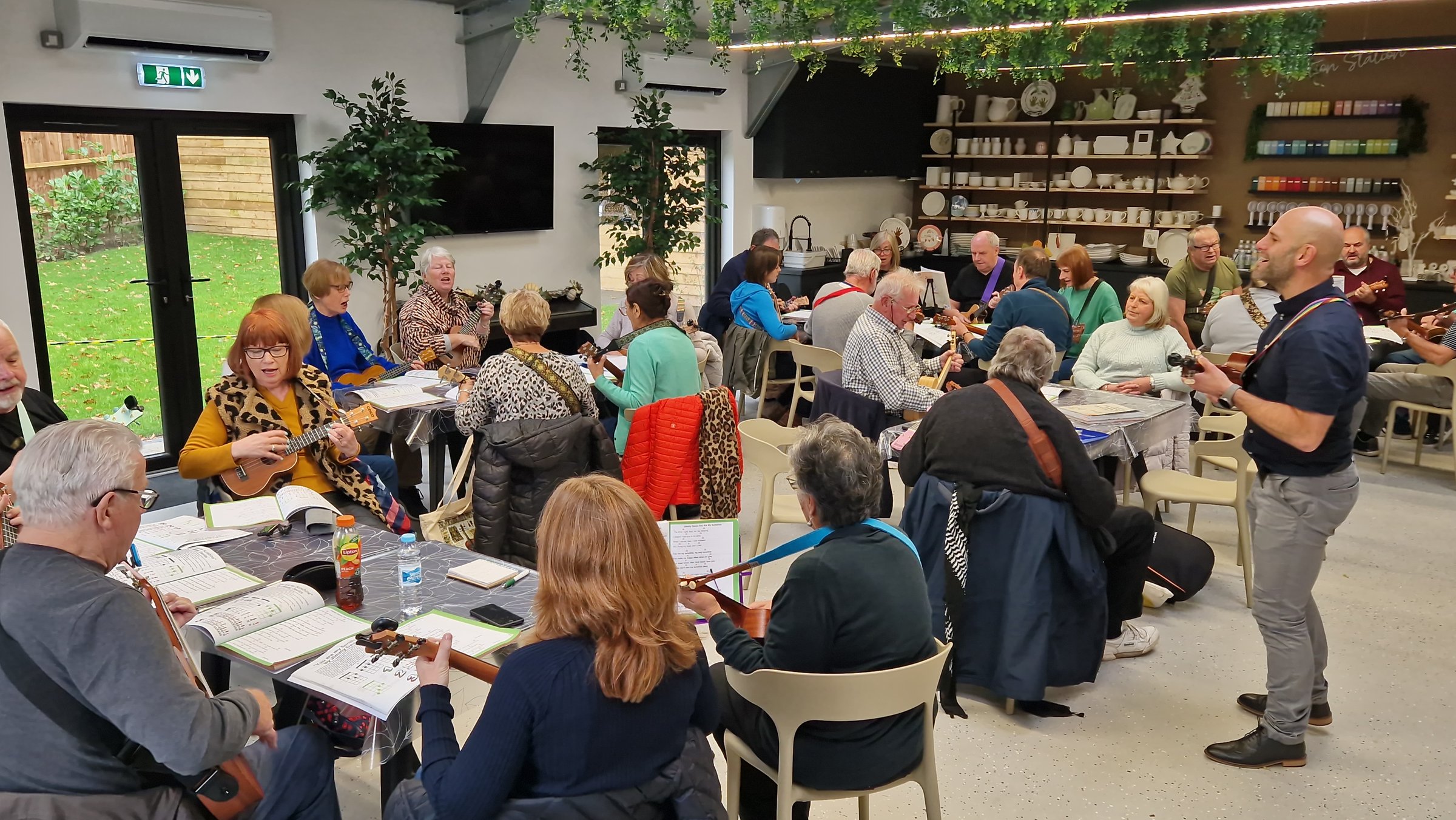 A real group of musicians gathered together in a room, playing ukuleles and making music side by side