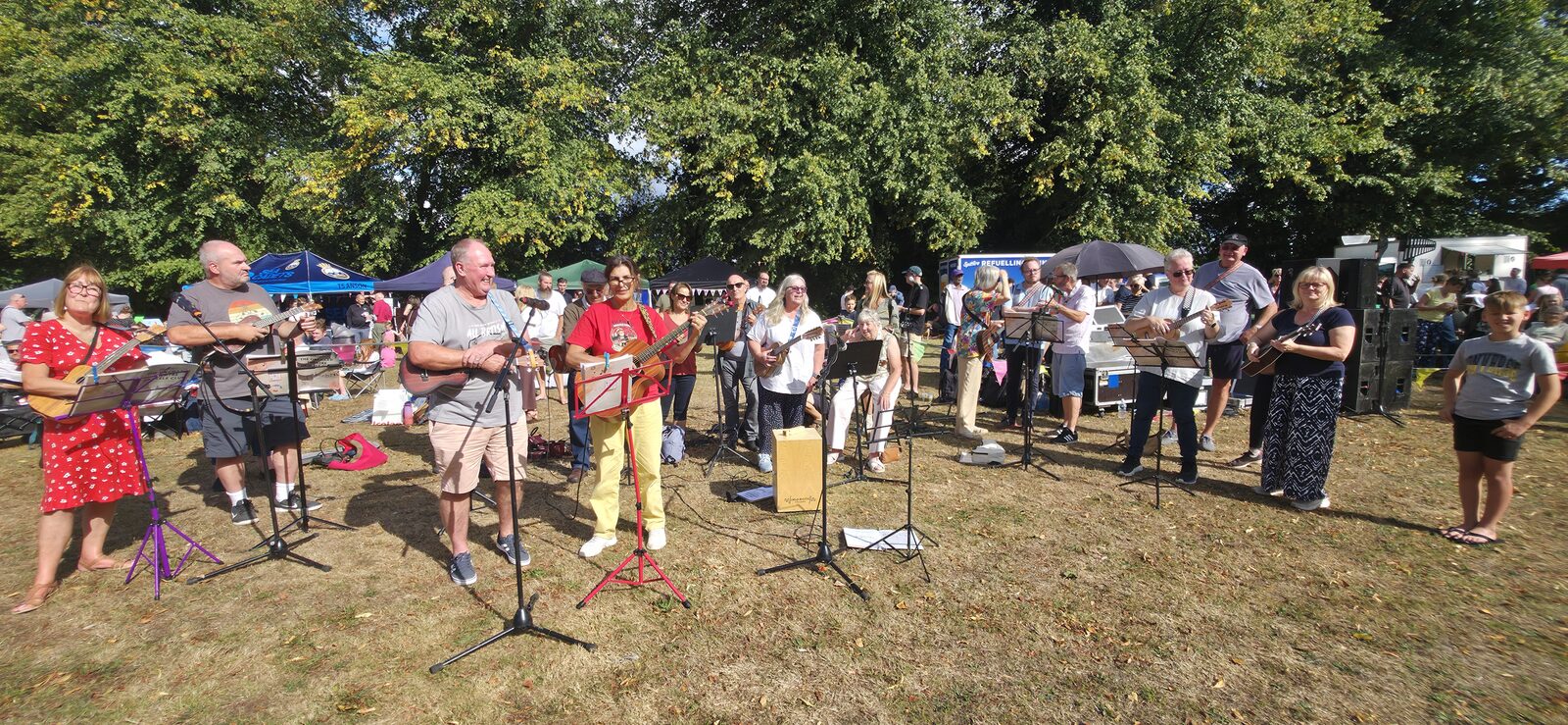 A ukulele group performing outdoors to a crowd at Wilmington Fair