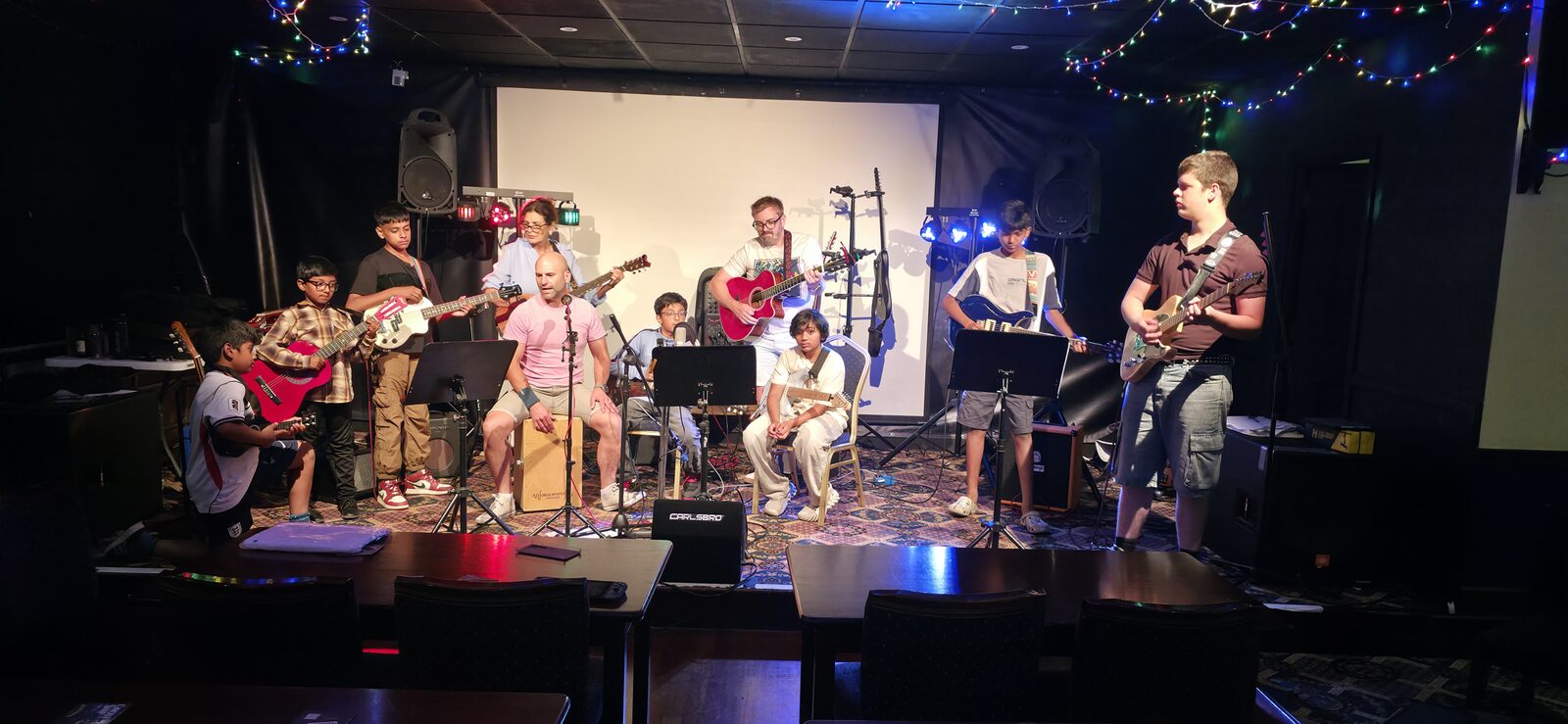 Young musicians performing together with guitars and bass on stage at the Working Men's Club, Dartford