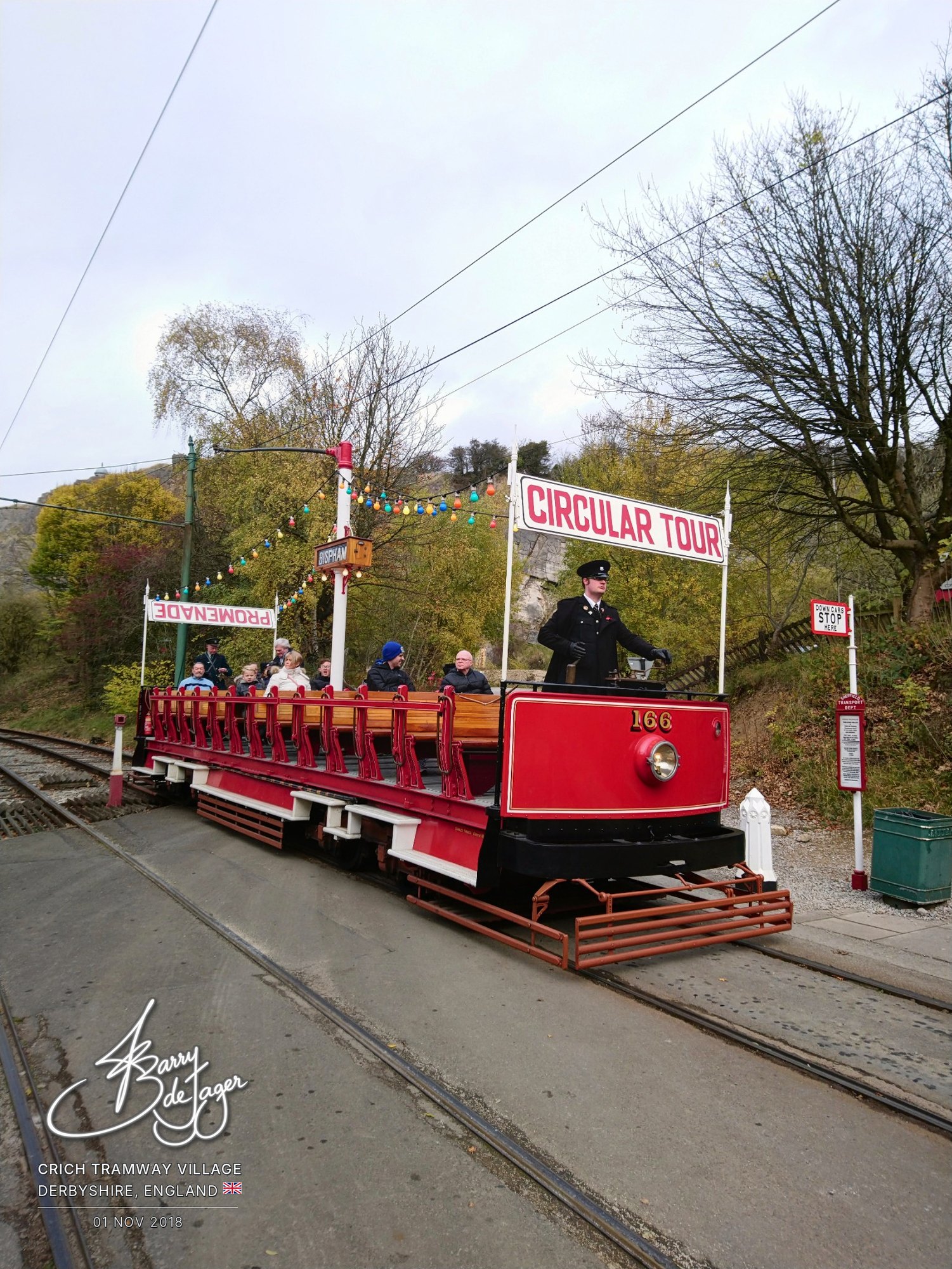 Open-top Circular Tour tram 166 with passengers and a uniformed driver at Crich Tramway Village