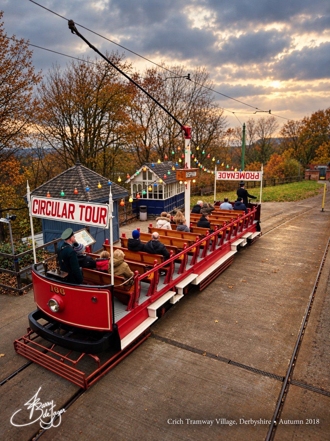 Circular Tour tram 166 under an autumn sky with strings of coloured bulbs, Crich Tramway Village