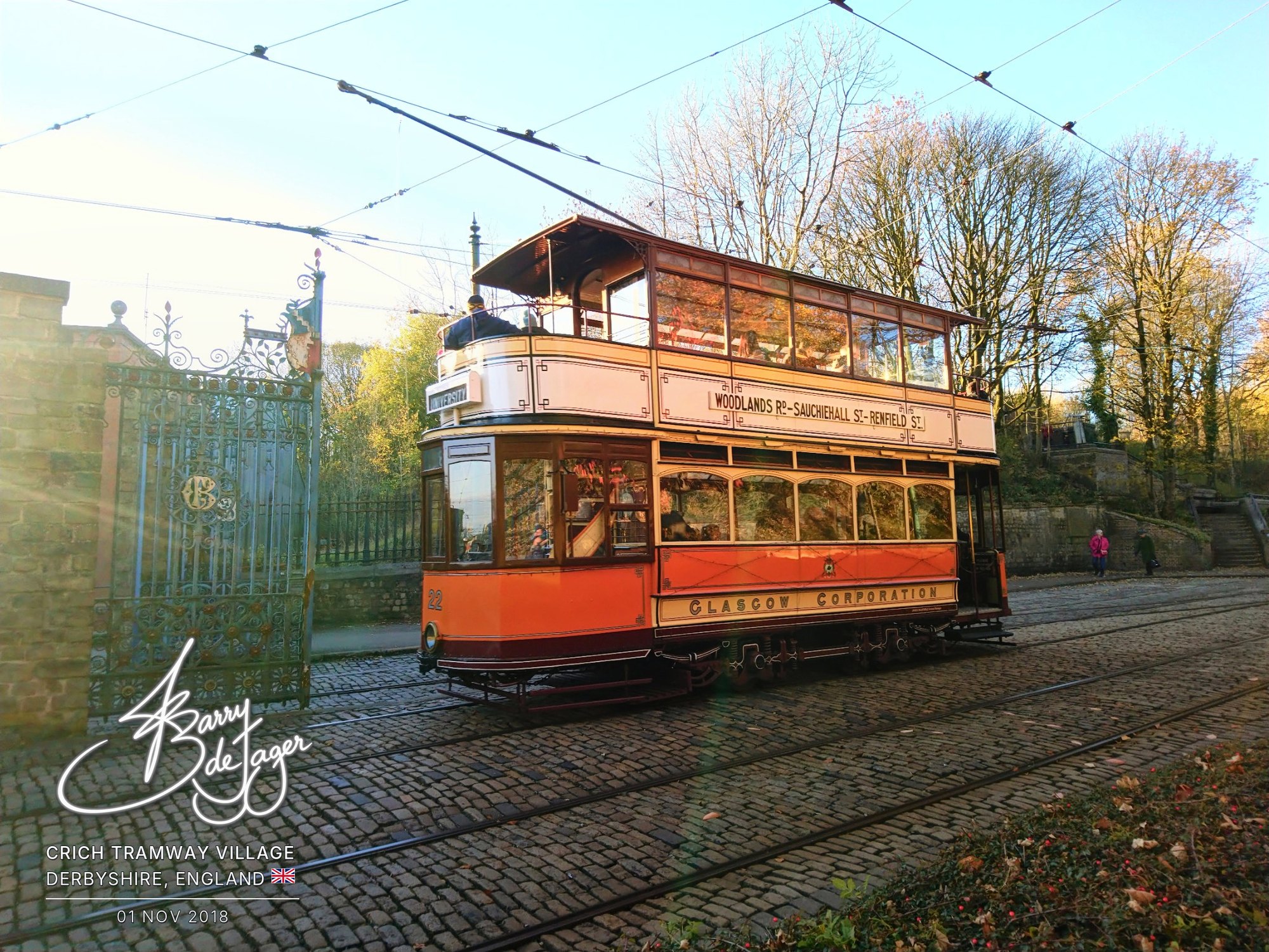 Glasgow Corporation tram 22 passing ornate iron gates in autumn sunshine at Crich Tramway Village