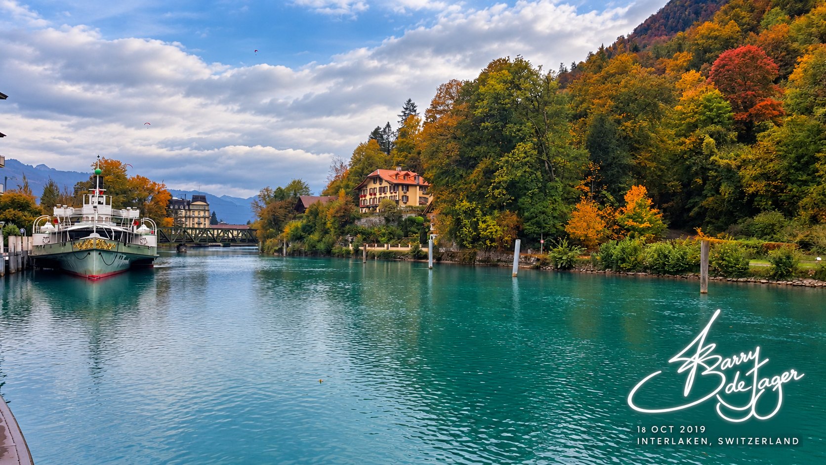 Interlaken river scene with a paddle steamer, a hillside chalet and vivid autumn trees under a blue sky