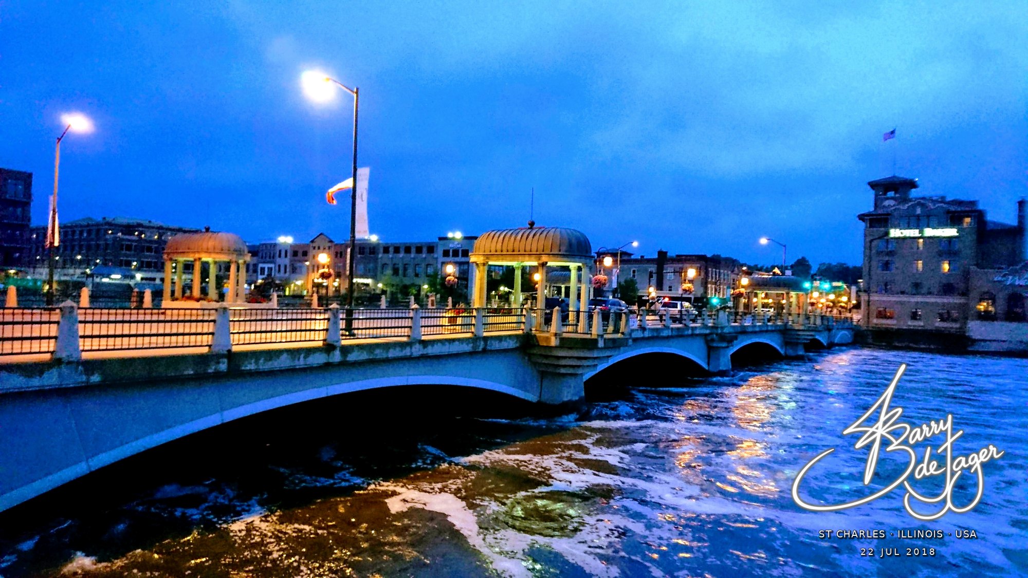 Lamp-lit bridge with domed pavilions over the Fox River at dusk in St Charles