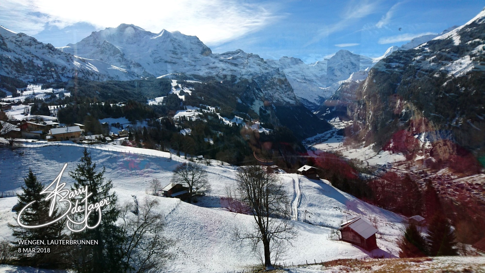 Snow-covered slopes and chalets above the Lauterbrunnen valley with towering alpine peaks, seen from Wengen